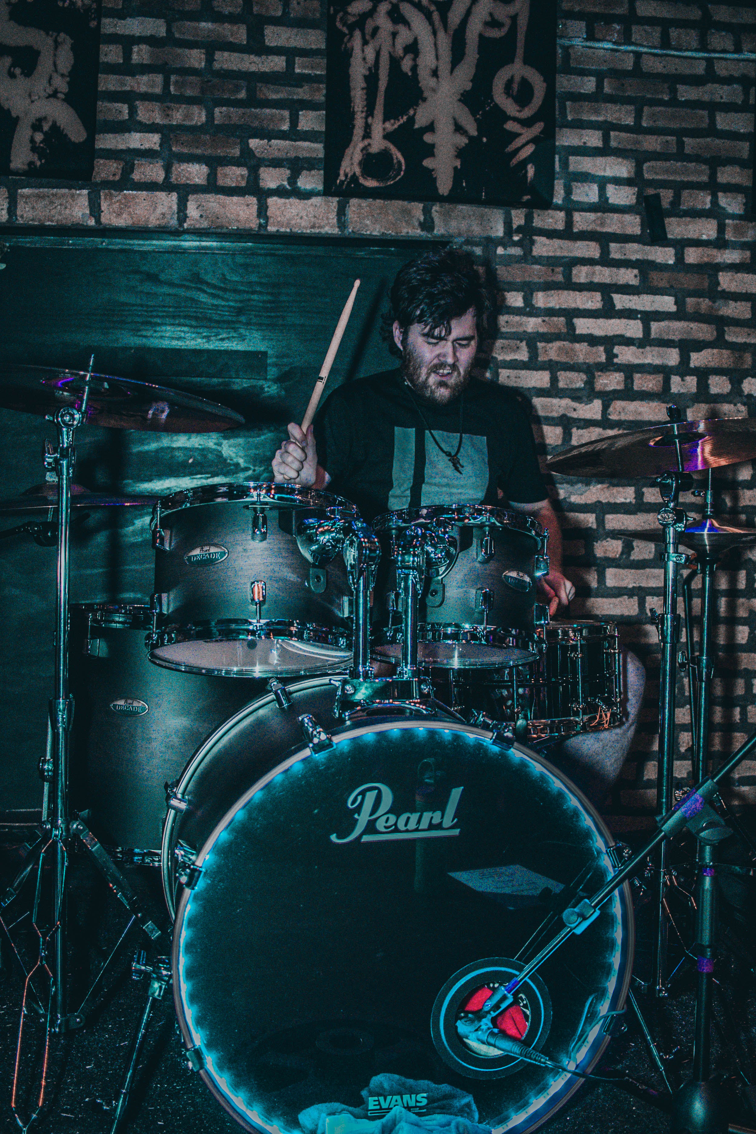 Sam behind the Pearl drum kit in teal lighting